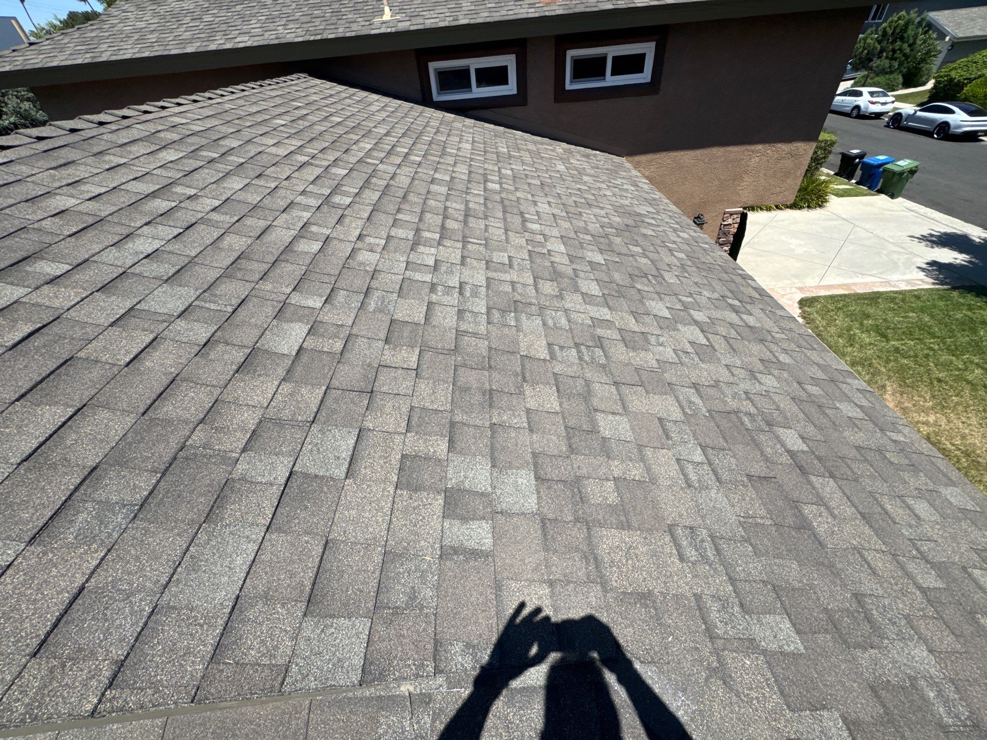 Roofers inspecting shingles and flashing on Pasadena residential roof after storm