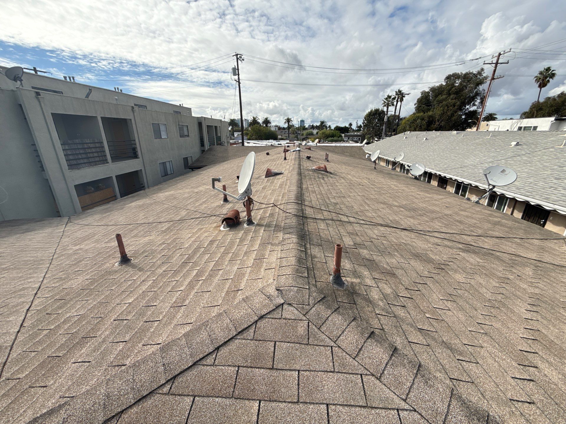 Professional roofer checking roof flashing and drainage on multi-story coastal property