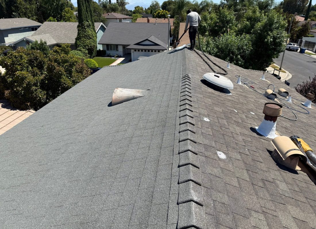 Roofing team replacing shingles on a large Van Nuys, CA apartment building under clear skies