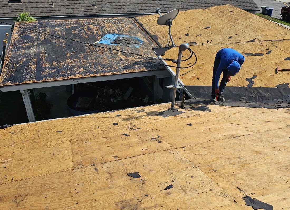 Roofing specialists inspecting decking and underlayment during full roof replacement project