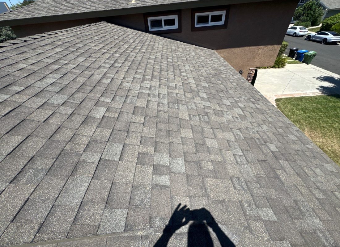 Roofers inspecting shingles and flashing on Pasadena residential roof after storm